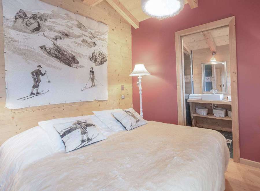 Experience the charm of this cozy bedroom, featuring a unique ski-themed artwork and warm wooden accents.