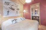 Experience the charm of this cozy bedroom, featuring a unique ski-themed artwork and warm wooden accents.