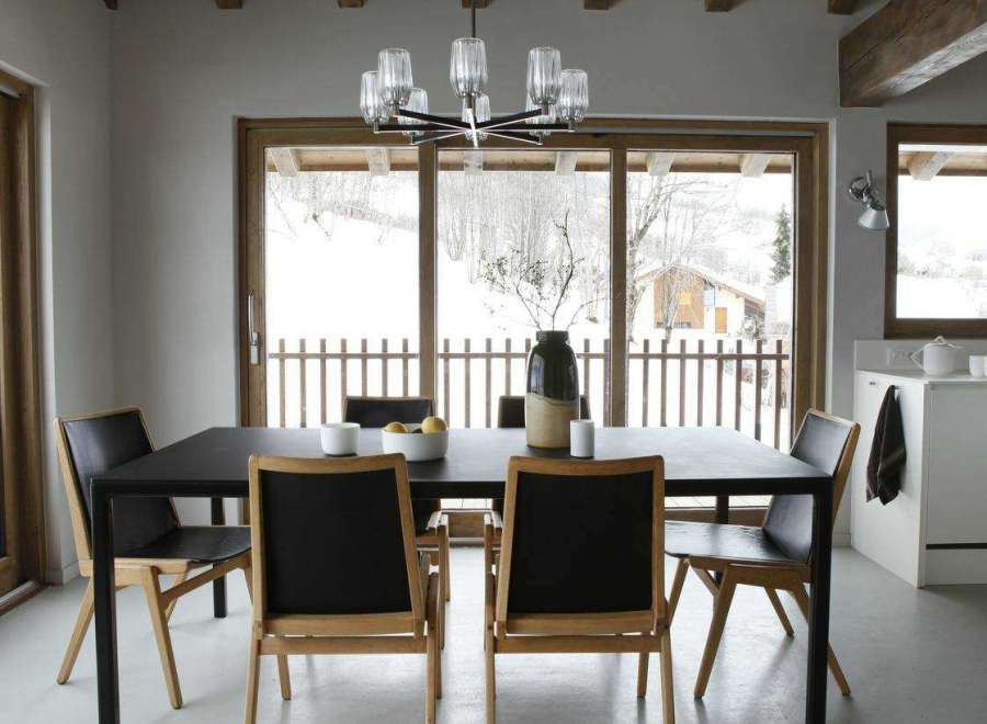 This dining room features a modern black table and chairs, complemented by a stylish chandelier.