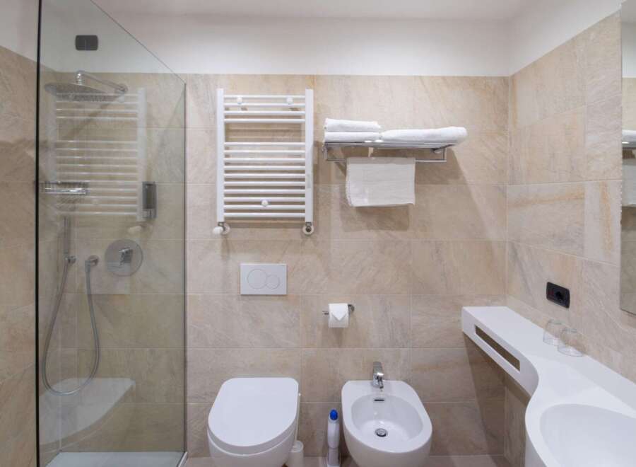 This modern bathroom features a sleek glass shower, a comfortable toilet, and a convenient bidet.