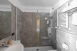 This modern bathroom features a sleek glass shower enclosure and stylish gray tile.