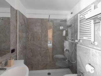 This modern bathroom features a sleek glass shower enclosure and stylish gray tile.