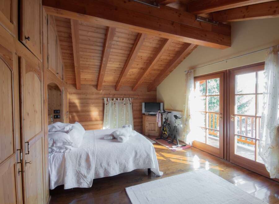 This cozy bedroom features a stunning wooden ceiling and walls, creating a warm and inviting atmosphere.