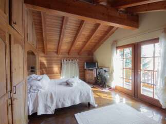 This cozy bedroom features a stunning wooden ceiling and walls, creating a warm and inviting atmosphere.
