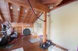 This stunning home gym boasts a rustic charm with its wooden beams and flooring.