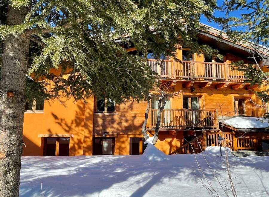 Discover a charming wooden chalet nestled in a snowy landscape.