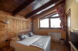 Cozy bedroom with wooden walls and ceiling, creating a warm and inviting atmosphere.