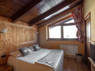 Cozy bedroom with wooden walls and ceiling, creating a warm and inviting atmosphere.
