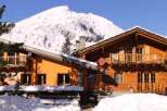 Experience the charm of a cozy wooden chalet nestled in a snowy mountain landscape.