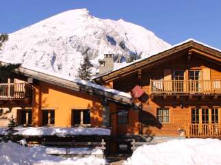 Experience the charm of a cozy wooden chalet nestled in a snowy mountain landscape.