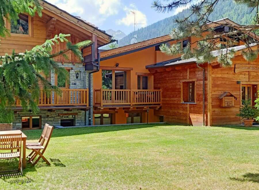 Discover the charm of this stunning chalet, featuring a beautiful wooden exterior and a lush green lawn.
