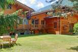 Discover the charm of this stunning chalet, featuring a beautiful wooden exterior and a lush green lawn.