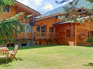 Discover the charm of this stunning chalet, featuring a beautiful wooden exterior and a lush green lawn.