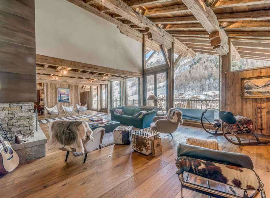 Experience luxury living in this stunning chalet, boasting a warm and inviting interior with exposed wooden beams and a cozy fireplace.