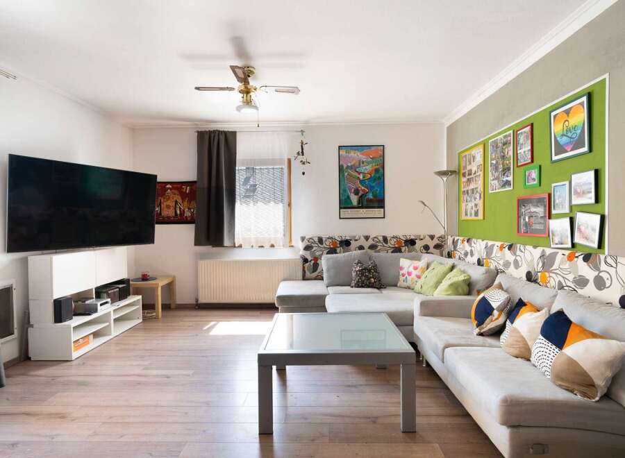 This inviting living room boasts a modern aesthetic with a large flat-screen TV, perfect for entertainment.