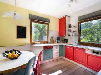 This charming kitchen boasts a vibrant and inviting atmosphere with its colorful cabinetry and ample natural light.
