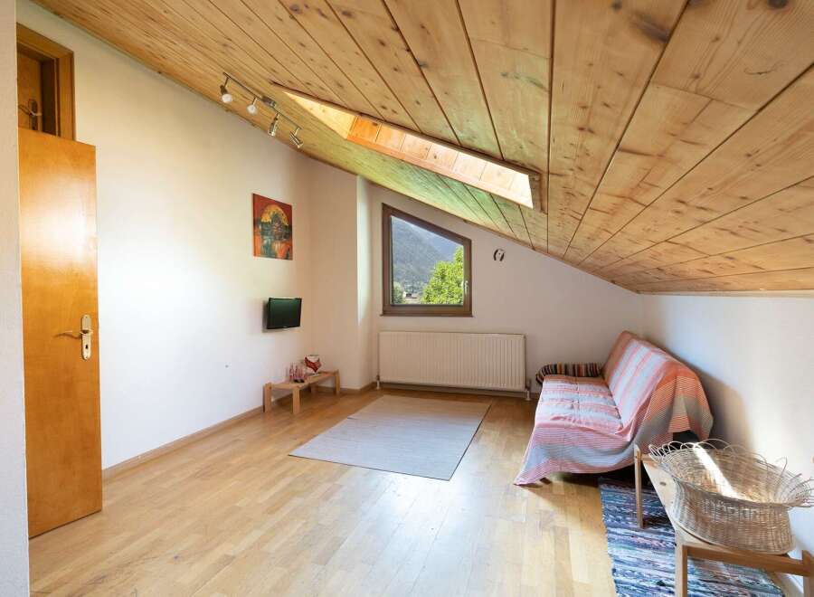 Discover a cozy retreat with a unique sloped ceiling and natural wood accents.