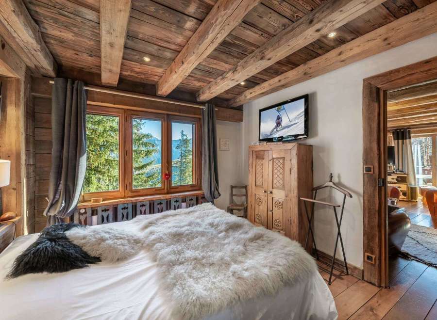 Experience rustic charm in this cozy bedroom, featuring a stunning wooden ceiling and a plush, inviting bed.