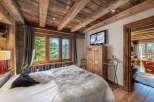 Experience rustic charm in this cozy bedroom, featuring a stunning wooden ceiling and a plush, inviting bed.