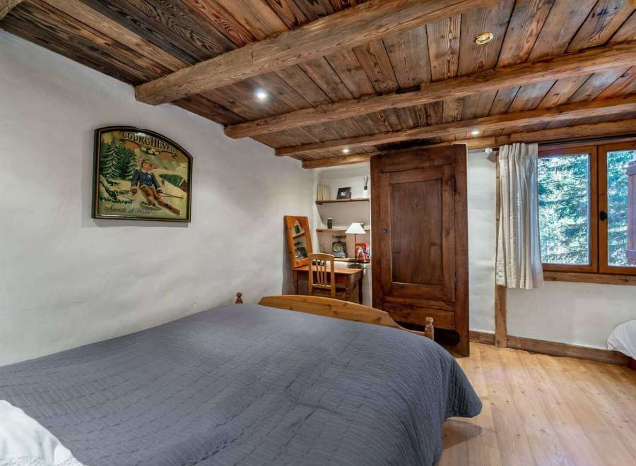 Experience rustic charm in this cozy bedroom, featuring a stunning wooden ceiling and warm wooden floors.