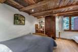 Experience rustic charm in this cozy bedroom, featuring a stunning wooden ceiling and warm wooden floors.