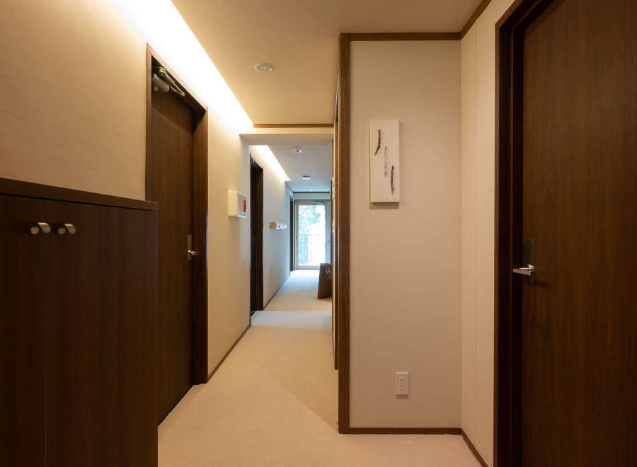 This hallway boasts a sophisticated design with dark wood doors and cabinetry, complemented by soft beige walls and carpeting.