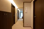 This hallway boasts a sophisticated design with dark wood doors and cabinetry, complemented by soft beige walls and carpeting.