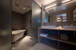 This modern bathroom boasts a spacious walk-in shower with frosted glass doors, a luxurious freestanding bathtub, and a sleek double vanity with ample storage.