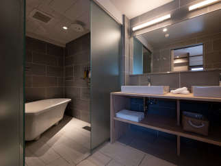 This modern bathroom boasts a spacious walk-in shower with frosted glass doors, a luxurious freestanding bathtub, and a sleek double vanity with ample storage.
