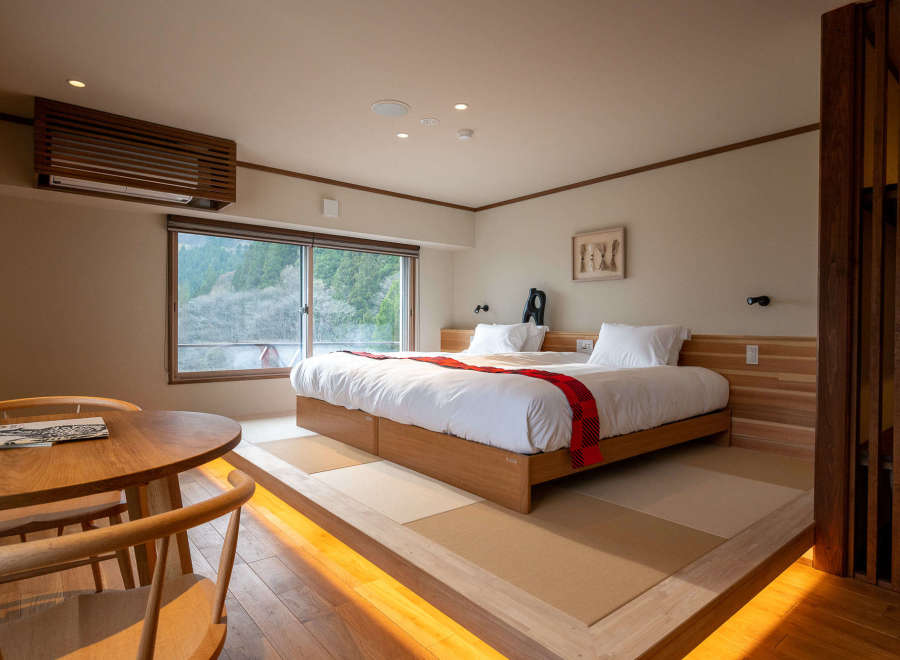 This stunning hotel room boasts a comfortable double bed with a cozy red blanket, situated on a raised platform with warm lighting.