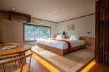 This stunning hotel room boasts a comfortable double bed with a cozy red blanket, situated on a raised platform with warm lighting.