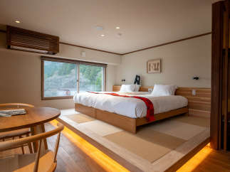 This stunning hotel room boasts a comfortable double bed with a cozy red blanket, situated on a raised platform with warm lighting.