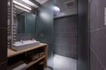 Modern bathroom with a walk-in shower, sleek gray tile, and a minimalist wooden vanity.