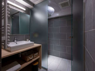 Modern bathroom with a walk-in shower, sleek gray tile, and a minimalist wooden vanity.