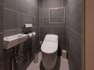 Modern bathroom with dark gray tile, wall-mounted sink and toilet, and sleek fixtures.
