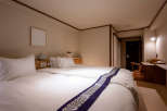 This cozy hotel room features a comfortable double bed with a stylish purple and silver patterned bed runner, perfect for a relaxing stay.
