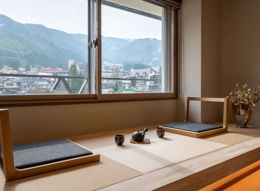 This serene room boasts a stunning mountain view through large windows, complemented by a minimalist tatami mat seating area perfect for relaxation.