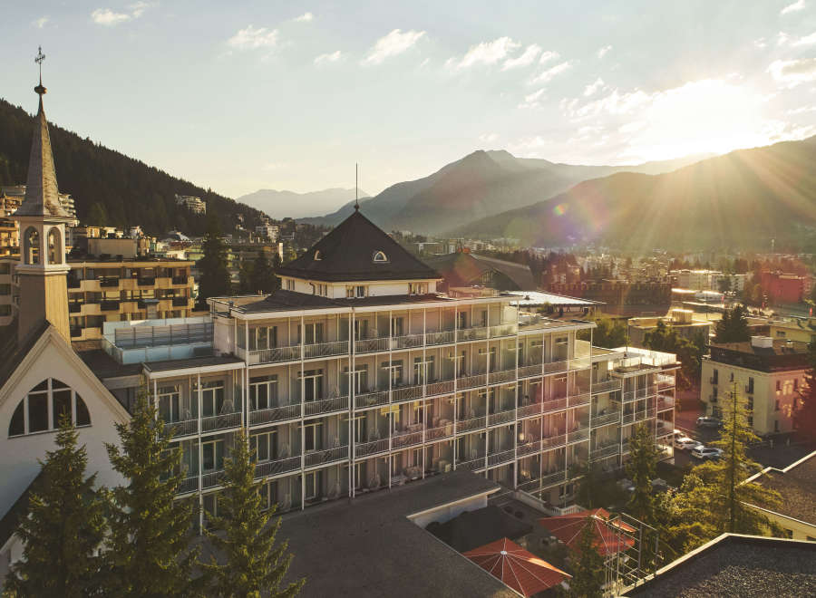 Nestled in a picturesque mountain setting, this stunning hotel boasts a unique architectural design, featuring a modern multi-story building with private balconies and a charming adjacent church.