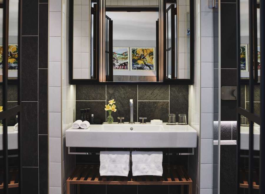 This modern bathroom boasts a sleek, white sink with a dark stone backsplash, complemented by white subway tiles.