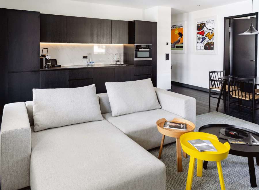 Modern apartment boasts a sleek, open-plan living area with a comfortable light grey sectional sofa and stylish side tables.