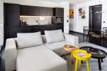 Modern apartment boasts a sleek, open-plan living area with a comfortable light grey sectional sofa and stylish side tables.