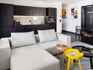 Modern apartment boasts a sleek, open-plan living area with a comfortable light grey sectional sofa and stylish side tables.