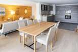 This stunning apartment boasts a spacious open-plan living area with a sleek modern kitchen and a large dining table perfect for entertaining.