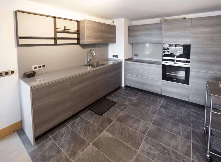 Modern kitchen with sleek gray cabinets and countertops.