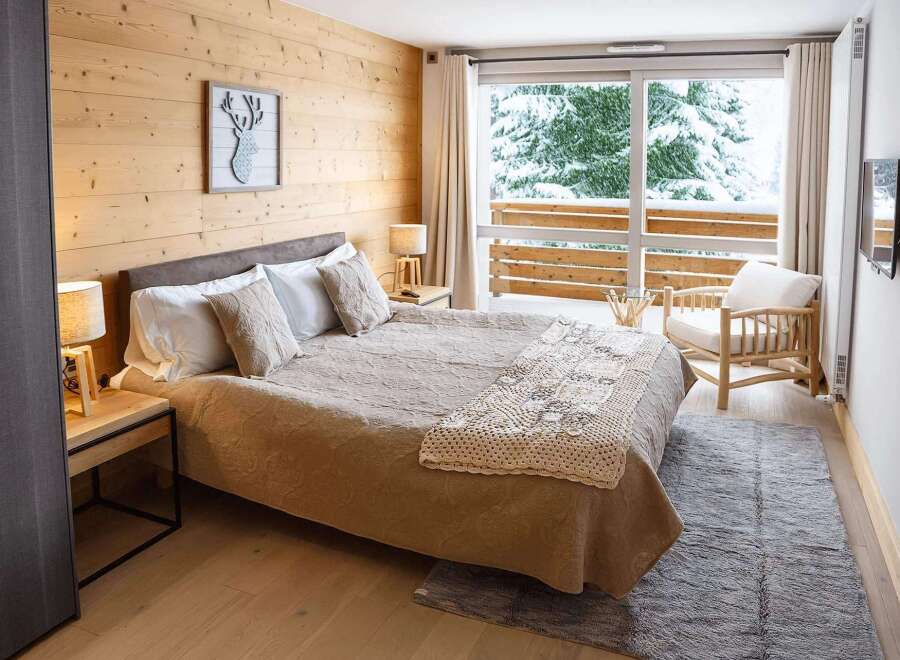 Cozy up in our chalet room featuring a king-size bed, wooden walls, and a stunning view of the snowy landscape.