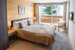 Cozy up in our chalet room featuring a king-size bed, wooden walls, and a stunning view of the snowy landscape.