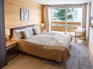Cozy up in our chalet room featuring a king-size bed, wooden walls, and a stunning view of the snowy landscape.