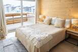 Cozy bedroom with a wooden wall and a view of a snowy landscape.