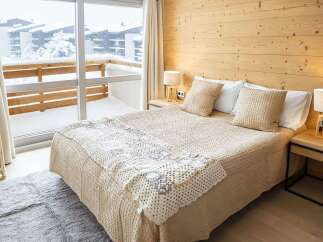 Cozy bedroom with a wooden wall and a view of a snowy landscape.