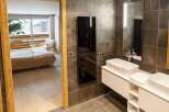 Luxurious bathroom with modern double sinks and heated towel rack, offering stunning views of a snowy mountain landscape from the adjacent bedroom.